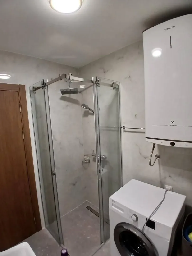 Moderne kupatilo sa tuš kabinom, bojlerom i veš mašinom.