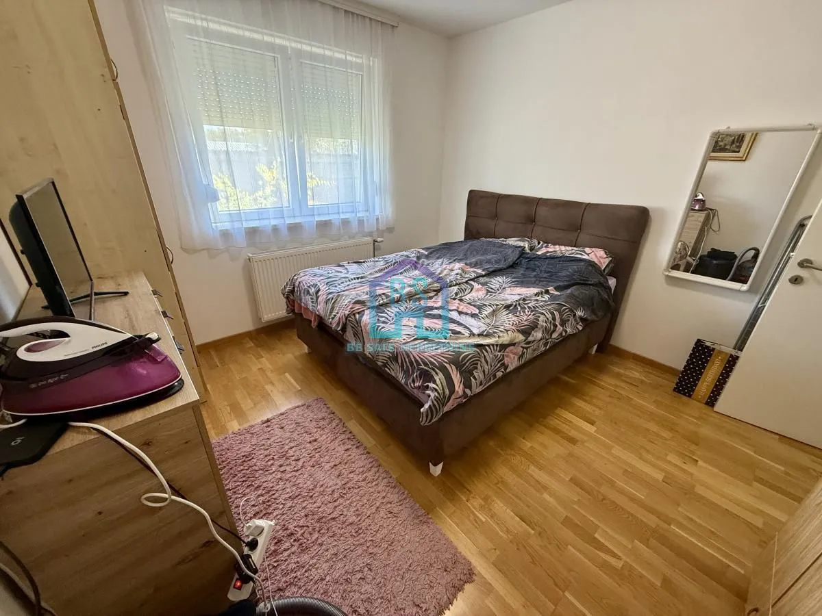 Nameštena spavaća soba sa bračnim krevetom i prozorom.