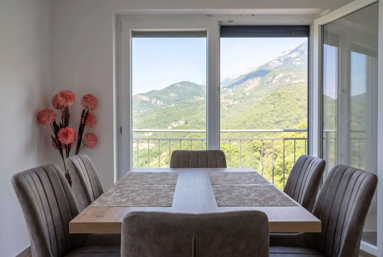 Dining area with a table, chairs, and a large window with a mountain view.