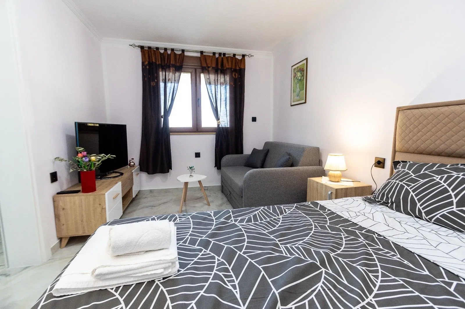 Furnished bedroom with a double bed, sofa, and TV.