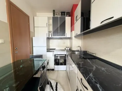Small kitchen with white cabinets, stove, and a dining table. - image 5