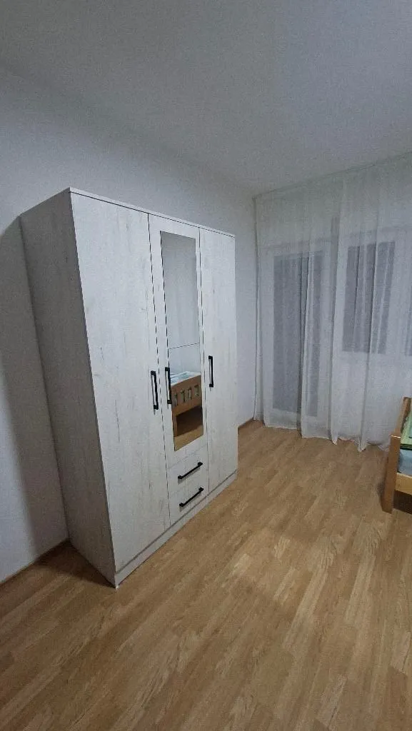 Spavaća soba sa velikim bijelim ormarom i drvenim podom.