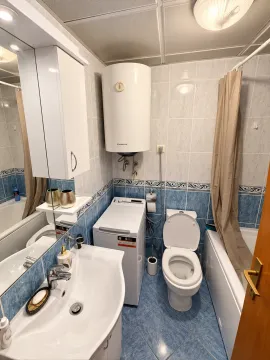 Compactly equipped bathroom with a bathtub, washbasin, washing machine, and water heater. - image 6