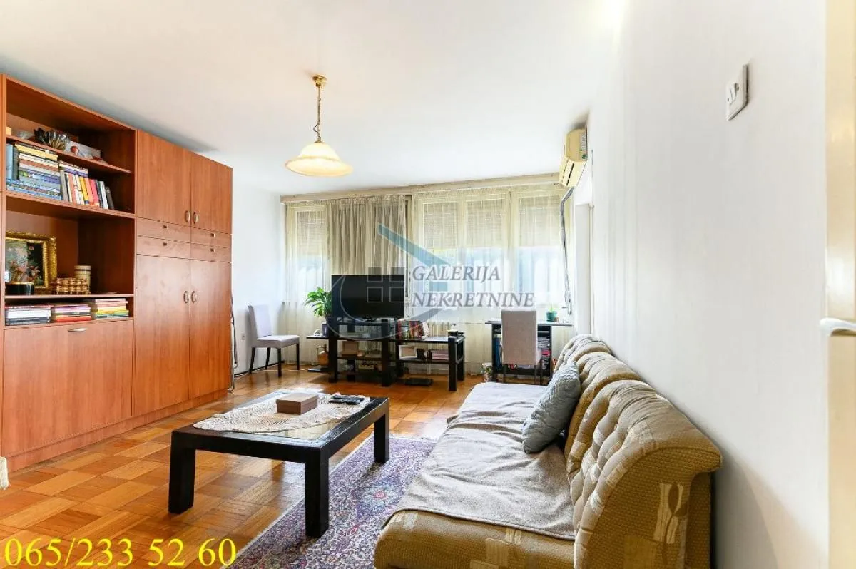 Dnevna soba sa garniturom, velikim drvenim ormarom i TV komodom.