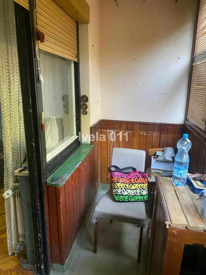 Zastakljeni balkon sa stolicom i drvenom oblogom na zidu.