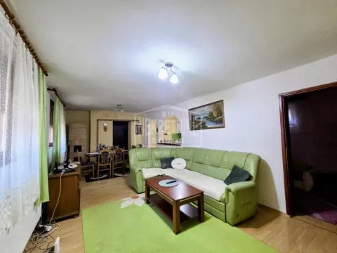 Dnevna soba sa zelenom ugaonom garniturom i trpezarijom u pozadini. - image 9