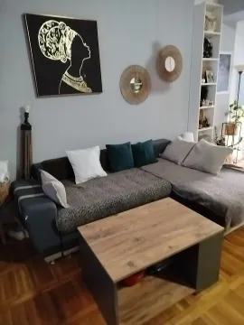 Dnevna soba sa ugaonom garniturom, stočićem i ukrasnim detaljima na zidu. - image 2