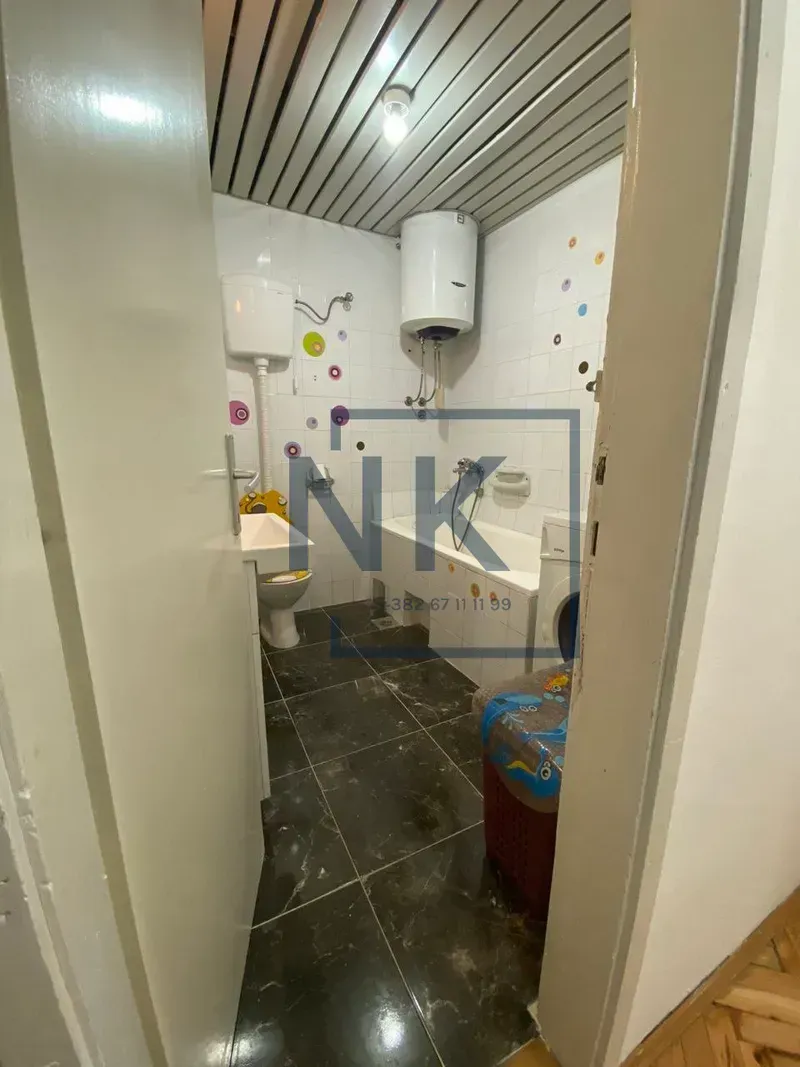 Manje kupatilo sa kadom, umivaonikom i bojlerom, slikano sa ulaznih vrata.