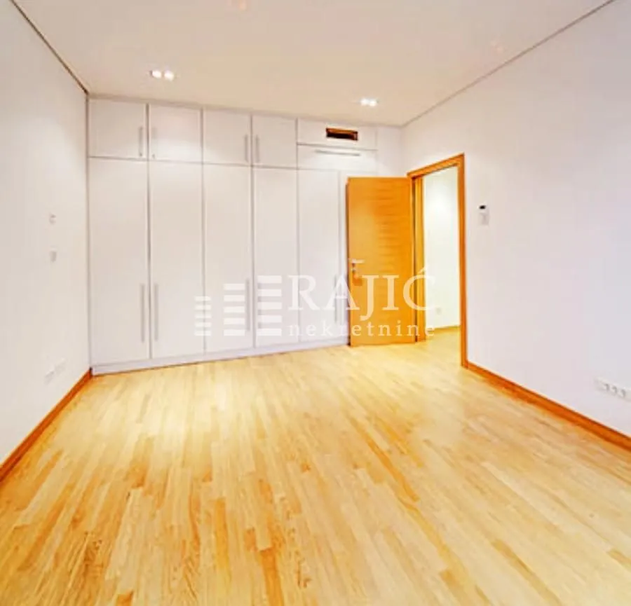 Empty bedroom with a built-in wardrobe and wooden flooring.