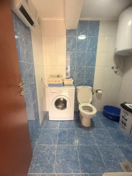 Manje kupatilo obloženo plavim i bijelim keramičkim pločicama sa veš mašinom. - image 10