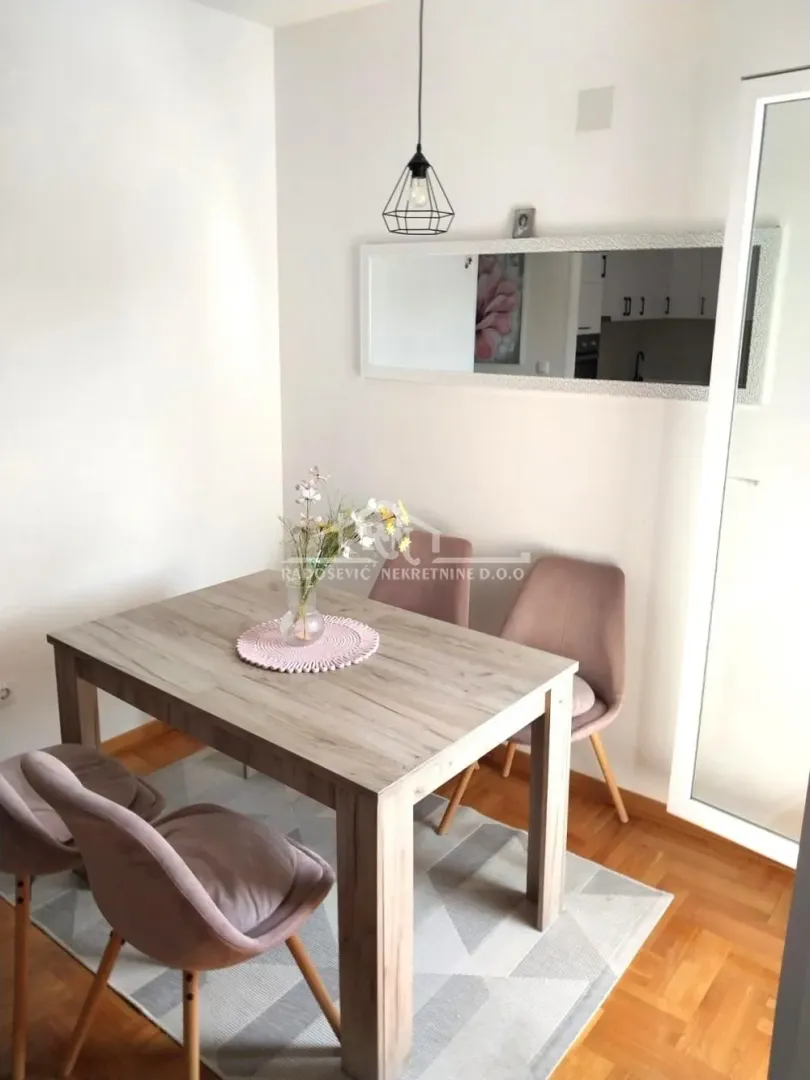 Dining area with a wooden table, chairs, and a wall mirror.