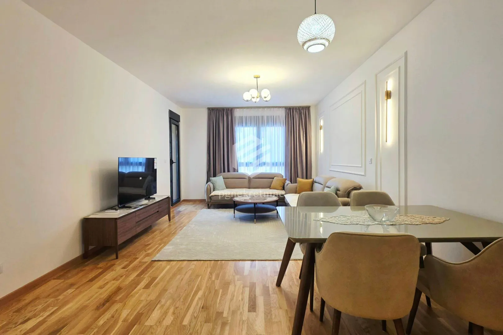 Spacious living room with sofa, TV and dining table.