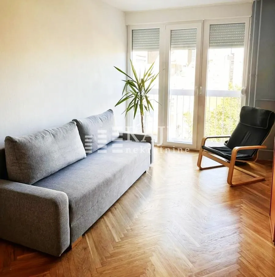 Living room with a sofa, armchair and parquet flooring.