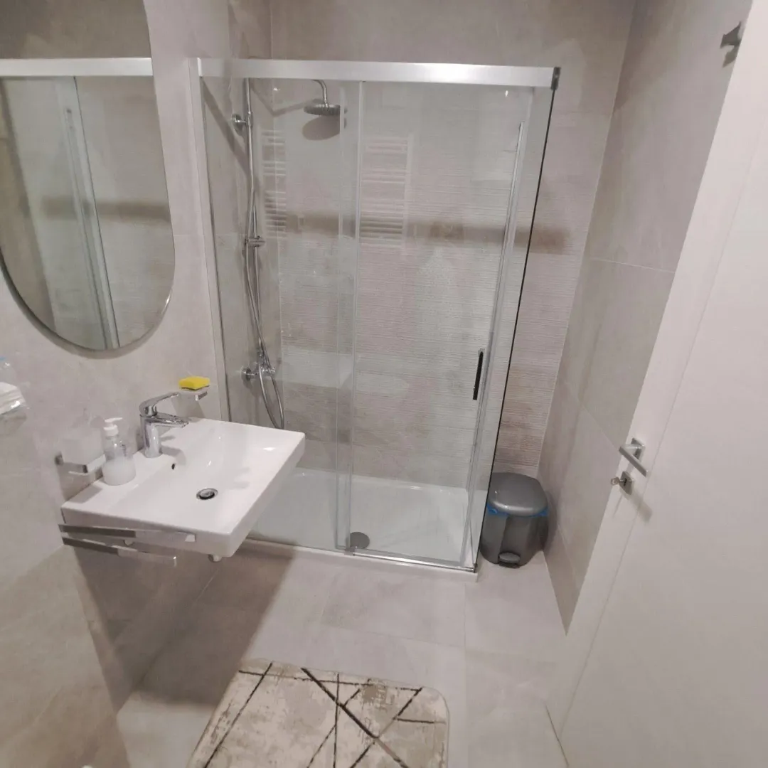 Smaller bathroom with a shower cabin, washbasin, and mirror.