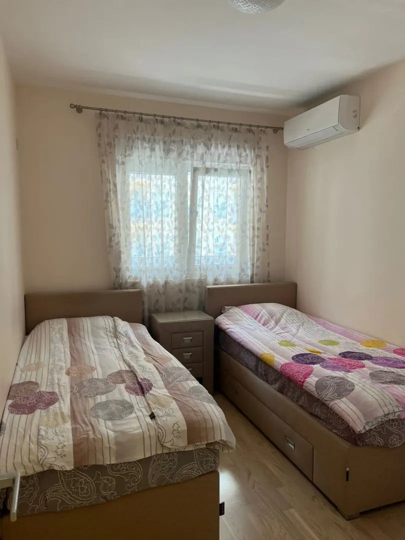 Spavaća soba sa dva singl kreveta, noćnim stočićem i klima uređajem.