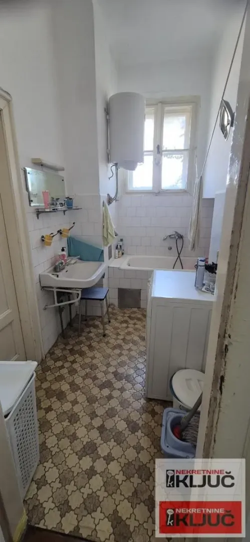 Pogled na kupatilo sa kadom, umivaonikom i veš mašinom.
