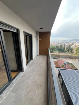 Prostrani popločani balkon sa staklenom ogradom i pogledom na okolinu. - image 2