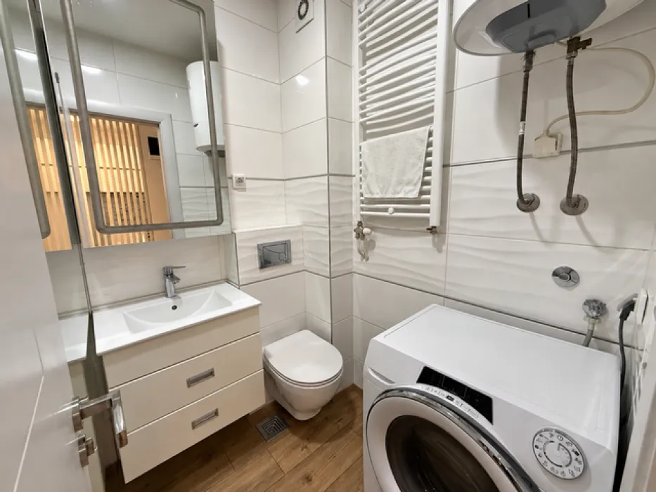 Compact bathroom with a washbasin, toilet, and washing machine.