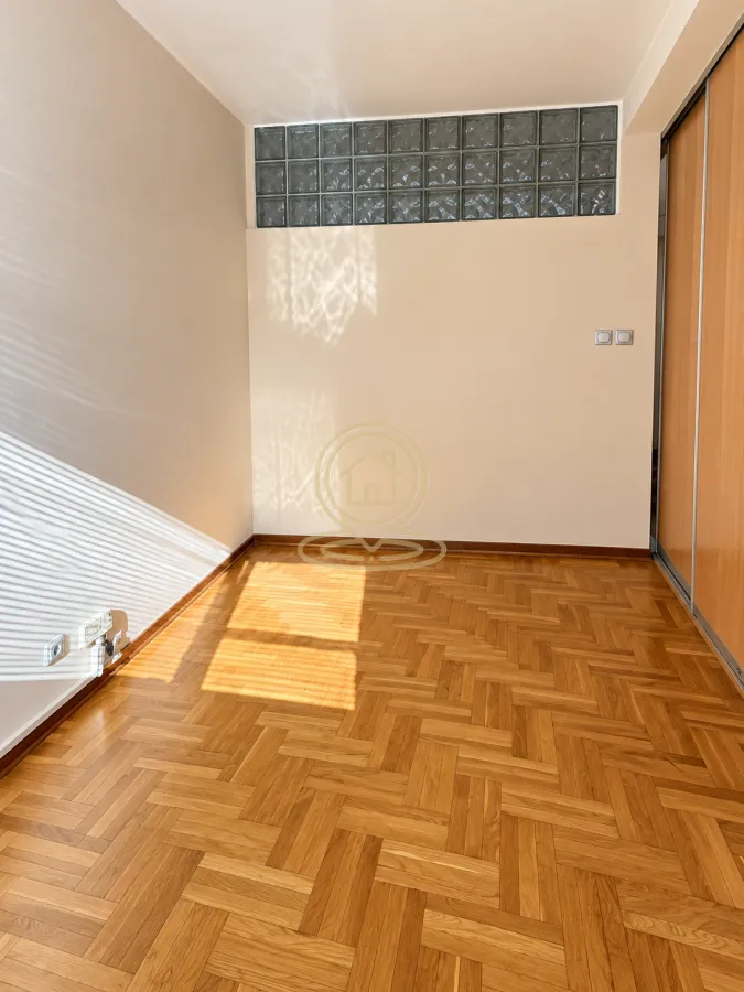 Empty room with parquet flooring and a built-in wardrobe.