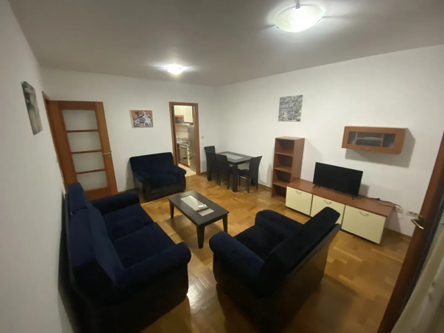 Living room with blue seating set, coffee table, and a dining table in the background.