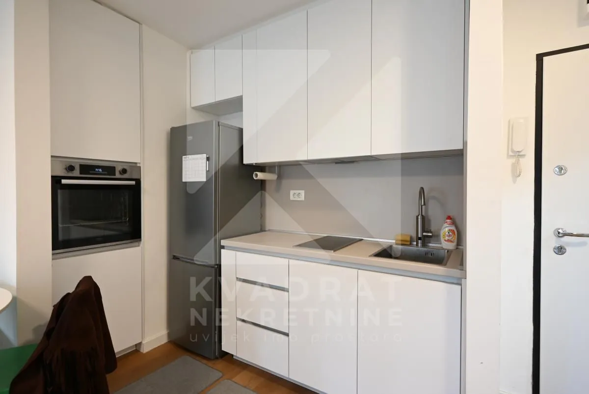 Small white kitchen with built-in refrigerator and oven.