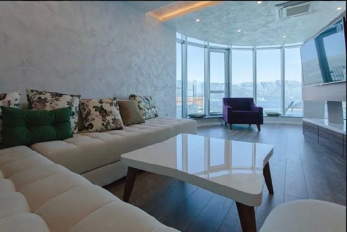 Spacious living room with a sofa, coffee table and large glass windows overlooking the sea.
