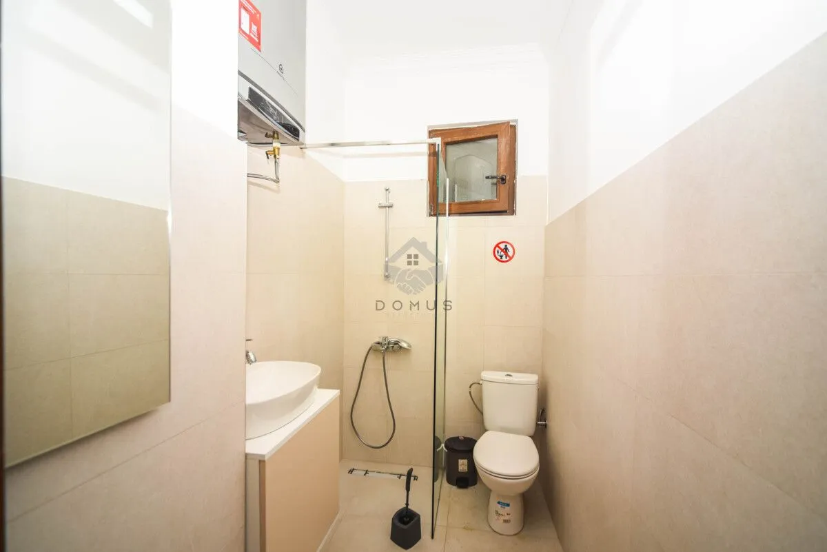 Bathroom equipped with a sink, toilet, and a glass-partitioned shower cabin.