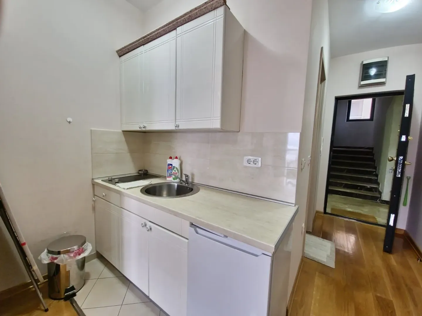Small white kitchen with a sink, cooktop, and refrigerator.