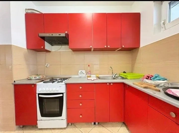 Small kitchen with red cabinets and a stove.