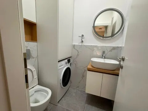 Moderne kupatilo sa umivaonikom, WC šoljom, mašinom za veš i okruglim ogledalom. - image 11