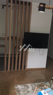 Living room with a wooden partition screen and a wall-mounted TV. - image 2