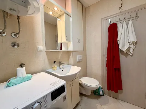 Kupatilo opremljeno umivaonikom, WC šoljom, mašinom za veš i ogledalom sa ormarićem. - image 10