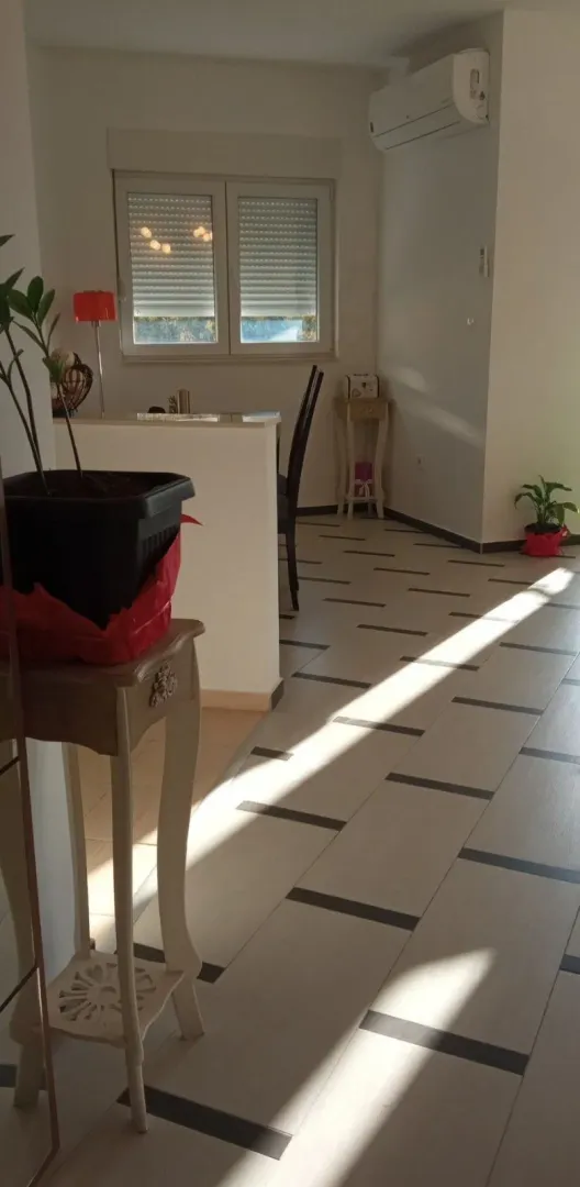 View of a bright living room with ceramic tile flooring and an air conditioner.
