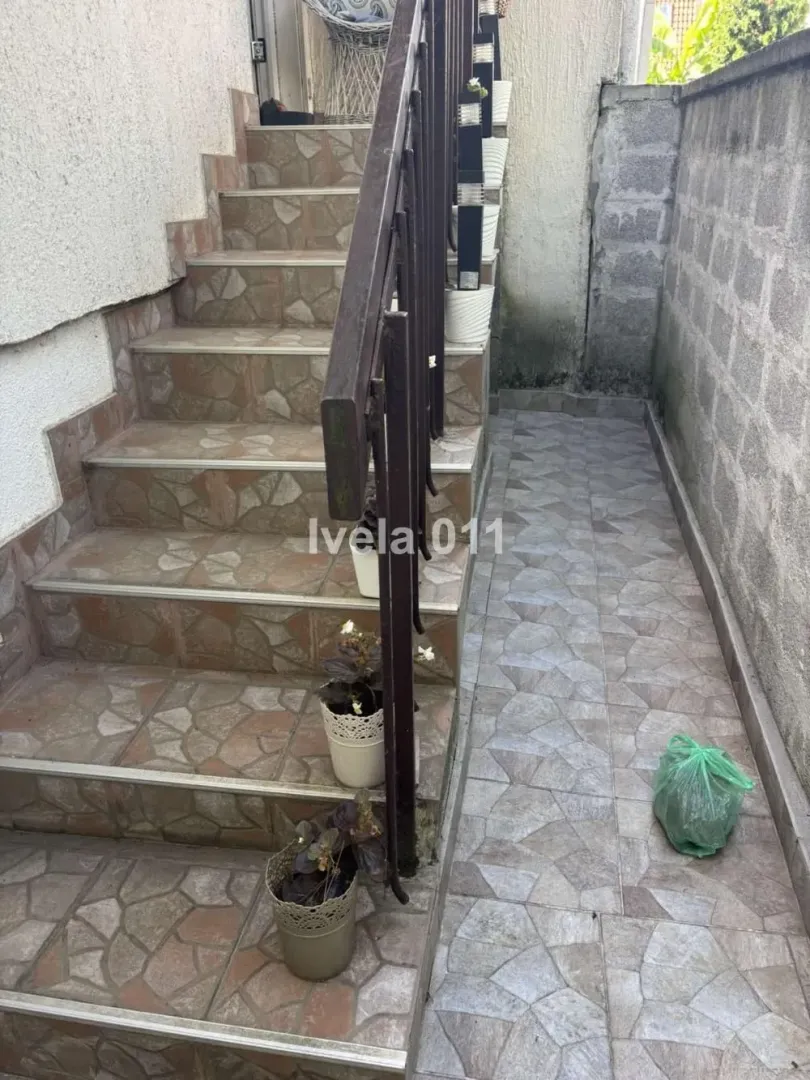 Exterior stairs with a railing and paved walkway next to the house.