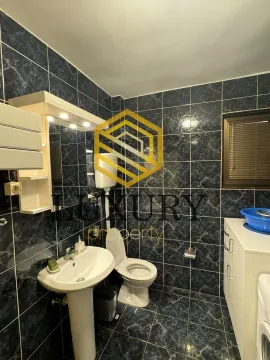 Manje kupatilo obloženo tamnim pločicama sa umivaonikom i toaletom. - image 15