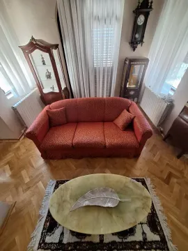Living room with a red sofa, parquet flooring, and traditional furniture. - image 6