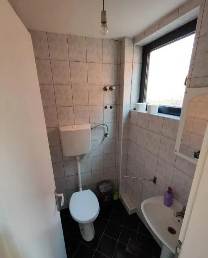 Manje kupatilo obloženo pločicama sa toaletom i umivaonikom.