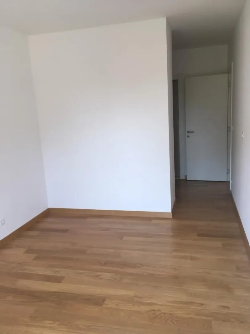 Empty room with white walls and wooden flooring.