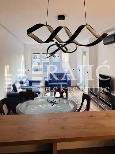 Living room with a sofa set, dining table, and modern chandelier.