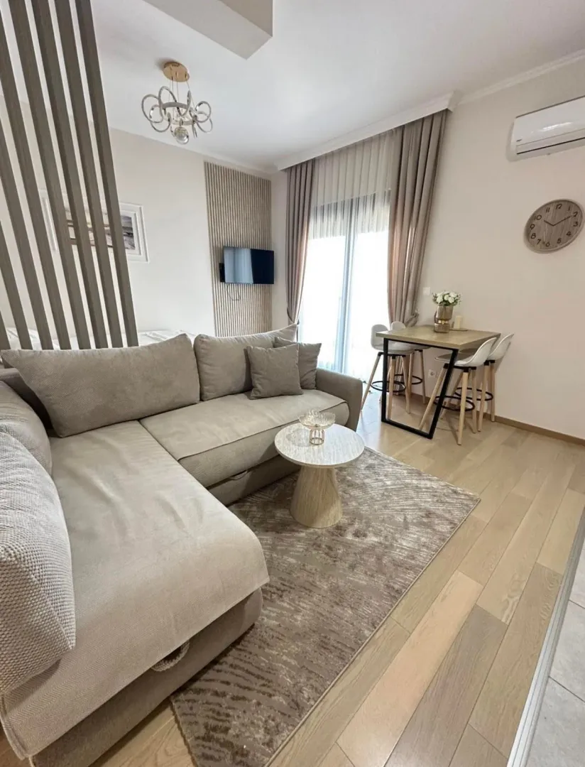 Modern living room with a sofa, dining table, and hardwood flooring.