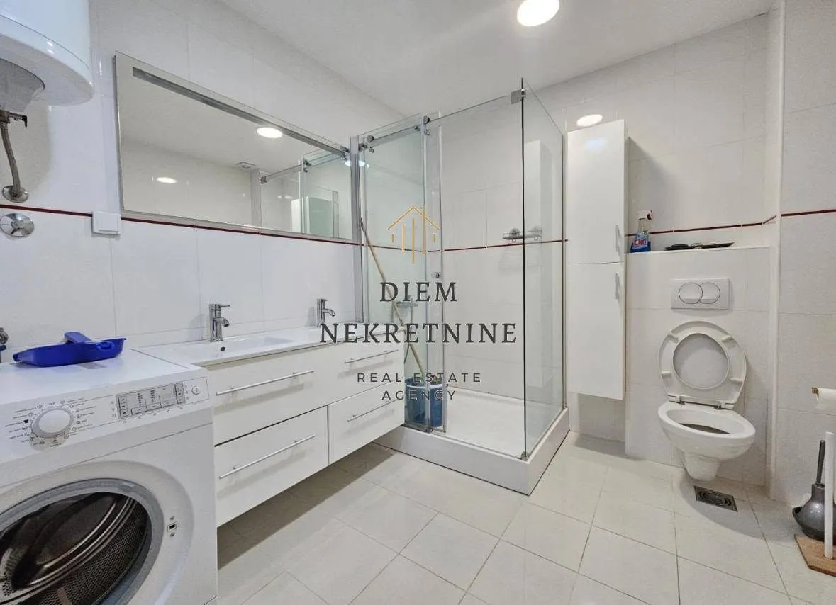 Modernly equipped bathroom with a shower cabin and washing machine.