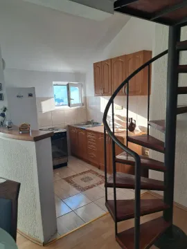 Manja kuhinja sa drvenim elementima i spiralnim stepenicama u prednjem planu. - image 4