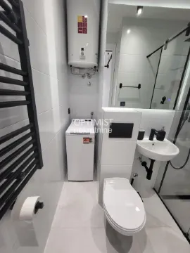 Manje kupatilo sa belim pločicama, tuš kabinom, umivaonikom i veš mašinom. - image 10
