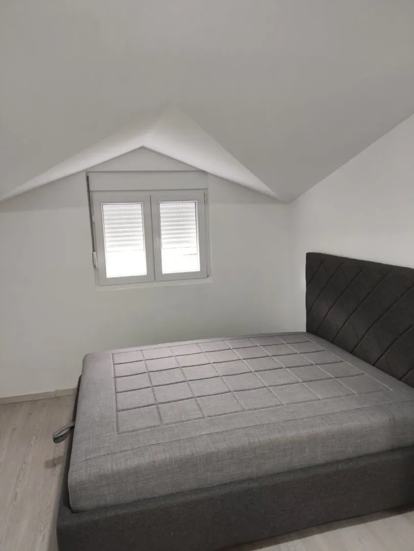 Bright attic bedroom featuring a modern grey bed.