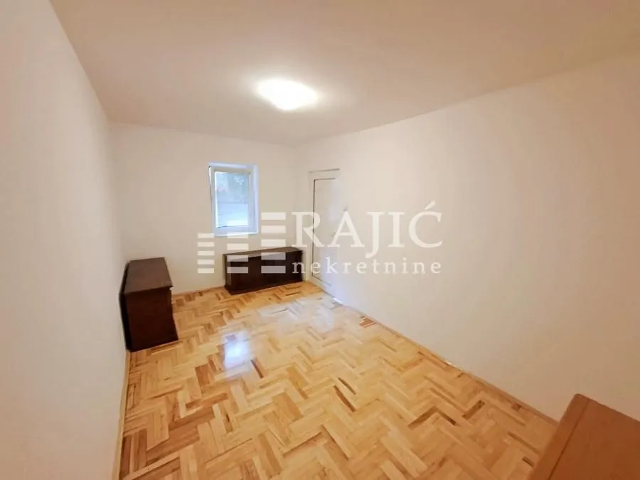 Empty room with parquet flooring and a window.