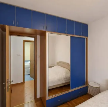 Spavaća soba sa velikim plavim ormarom i krevetom. - image 7
