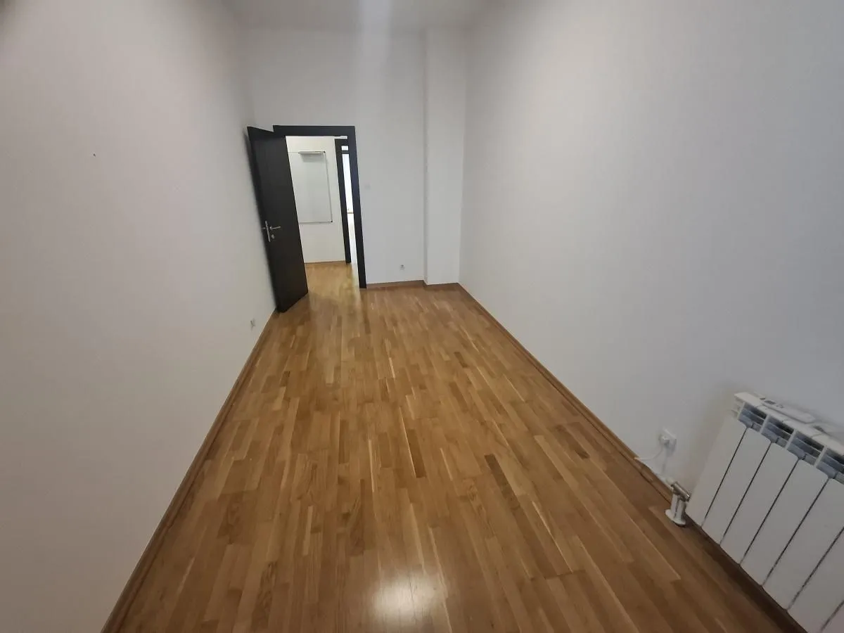 Prazna soba sa parketom i otvorenim vratima.