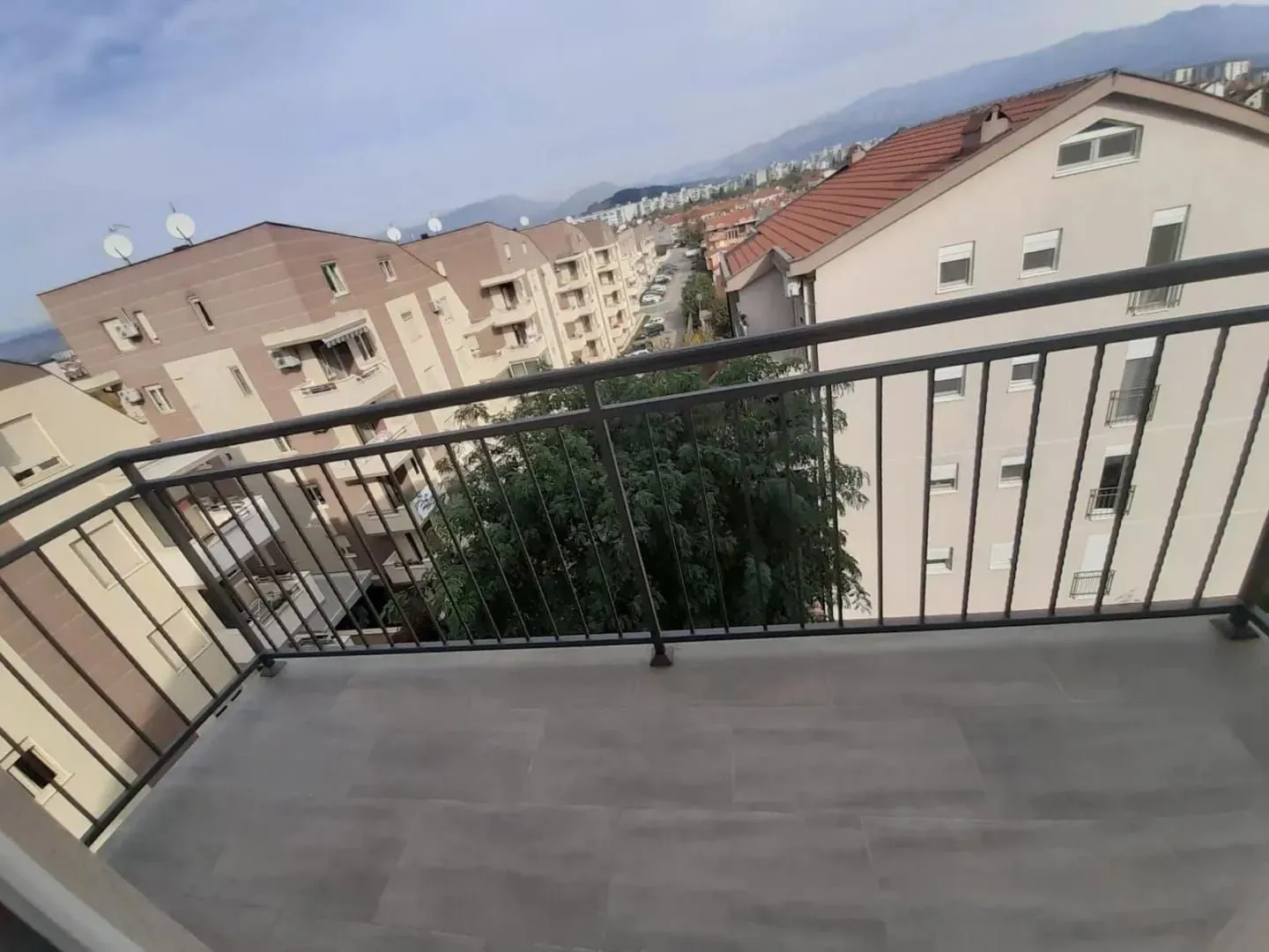 Spacious balcony with a view of surrounding buildings and neighborhood.