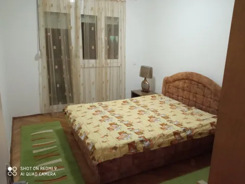A simply furnished bedroom with a double bed and a green rug. - image 6
