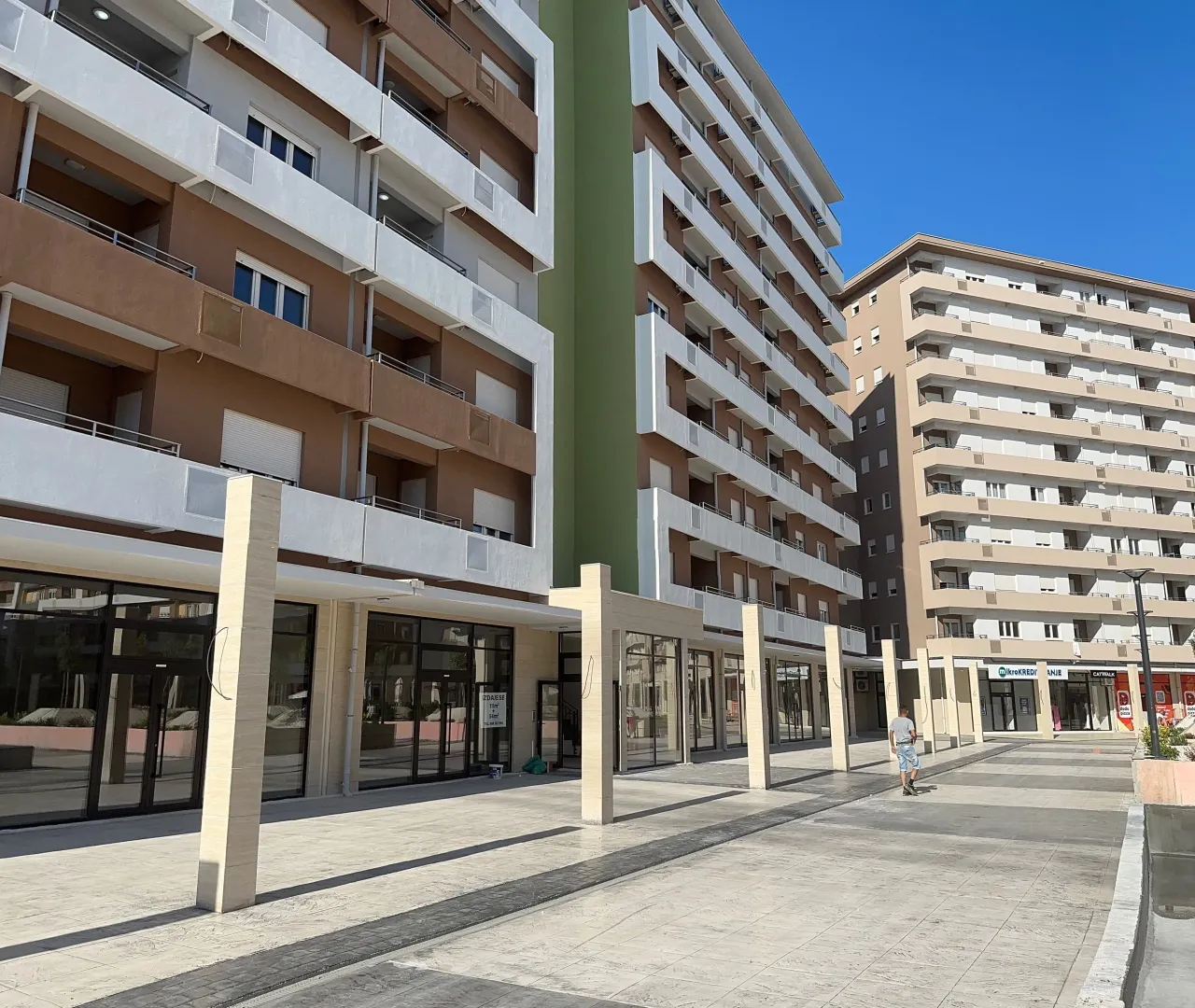 Spoljašnji izgled modernih stambenih zgrada sa uređenim platoom u prizemlju.
